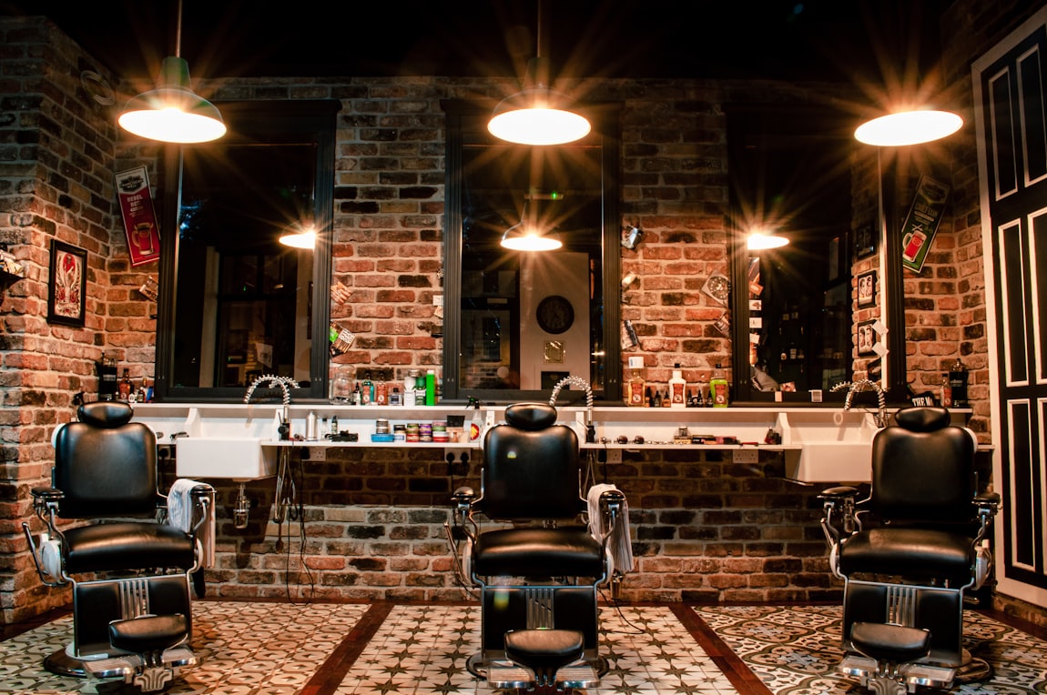 Warm, brick-walled interior of Iron Edge Barbershop with vintage barber chairs