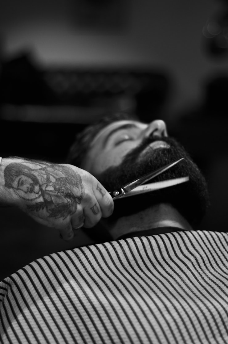 Black and white close-up of a beard being shaped with scissors